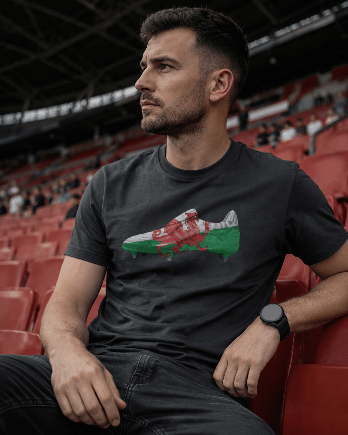 Man sitting in an empty stadium wearing a black t-shirt with a graphic design.