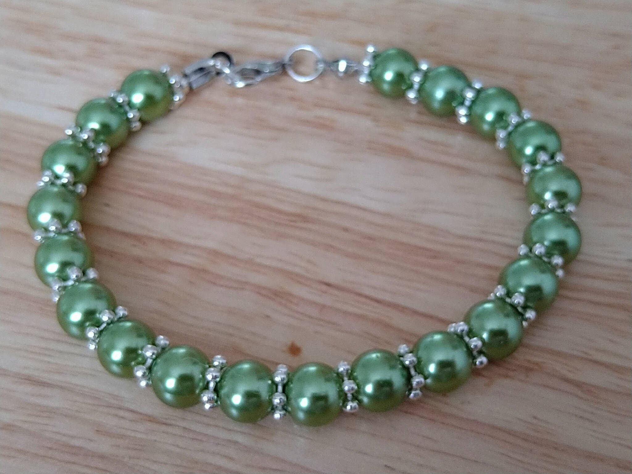 Green bracelet with silver coloured daisy spacers. Recycled beads