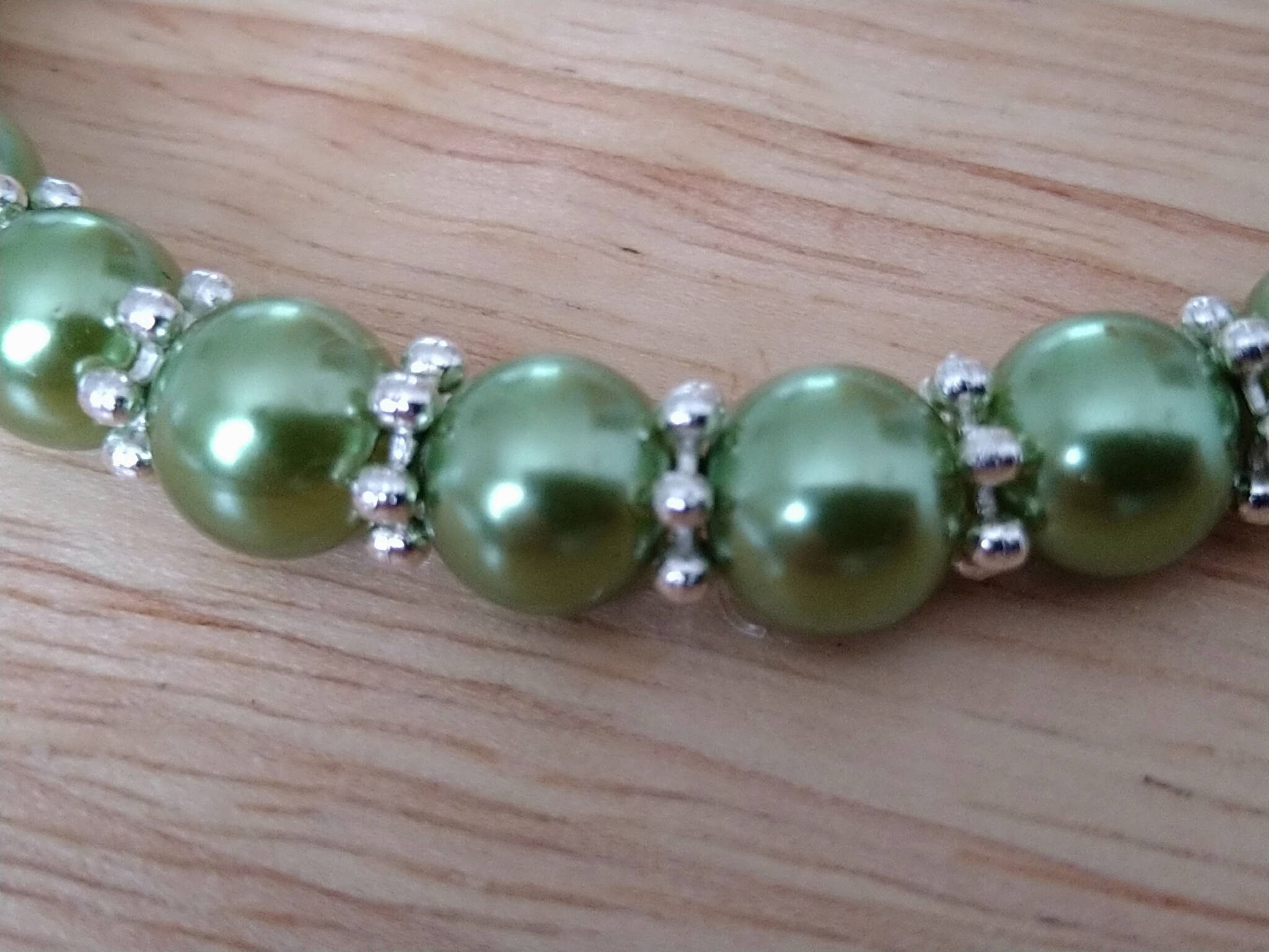 Green bracelet with silver coloured daisy spacers. Recycled beads
