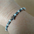 Single strand silver toned memory wire bangle with black & silver coloured beads, 6.5cm diameter